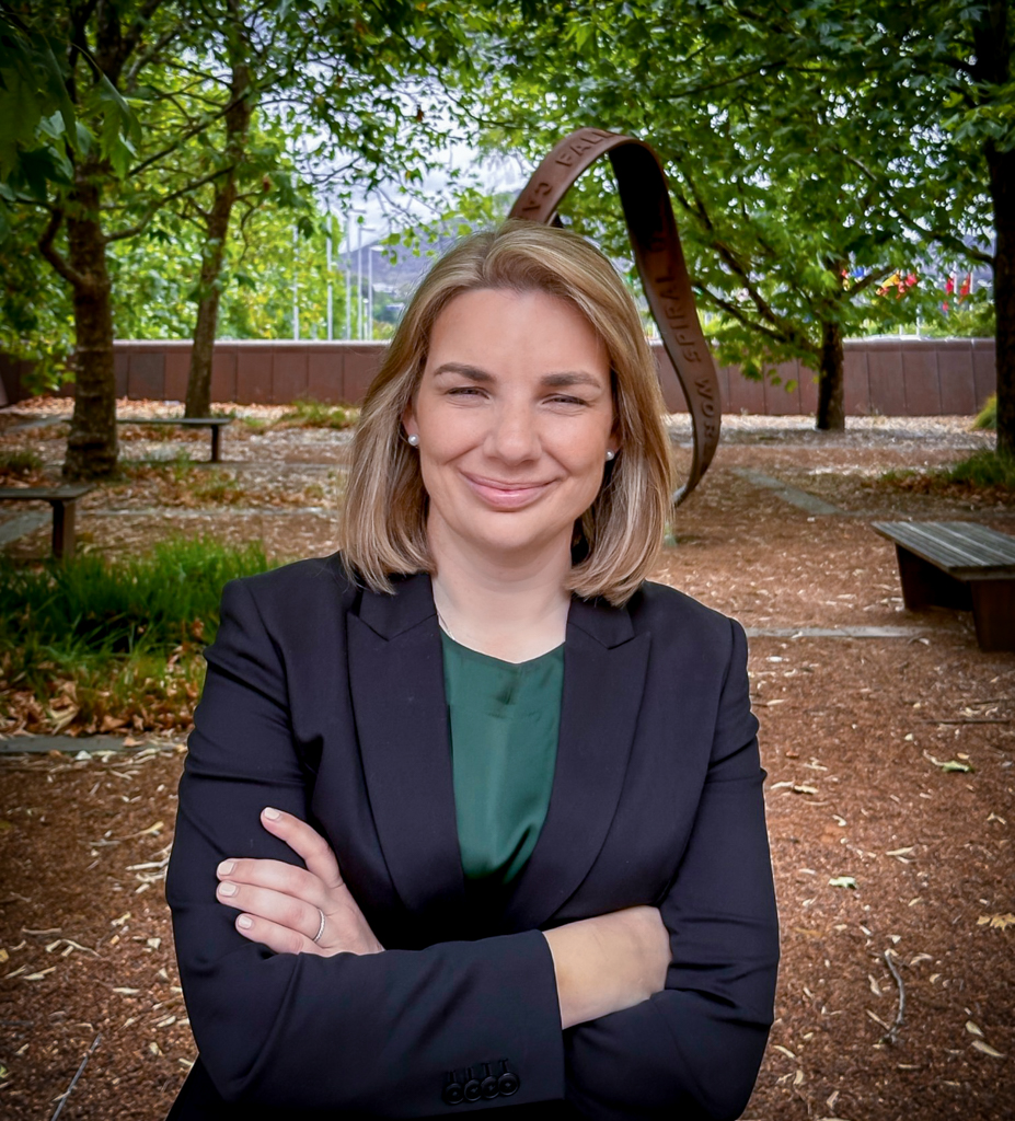 Head shot profile of a professional woman smiling with her arms crossed. 