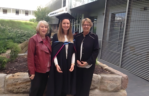 Young woman in graduation uniform stands between her Grandmother and Mother for a graduation photo.