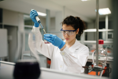 UNE student in white lab coat performs an experiment