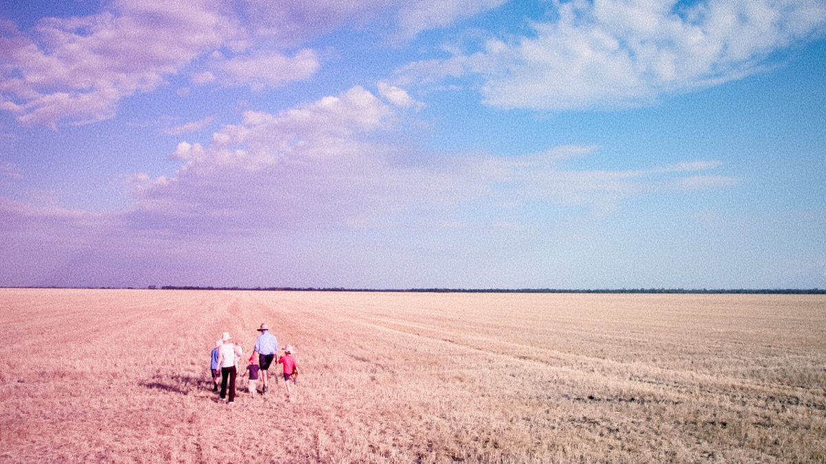 Family walking through a harvested wheat field